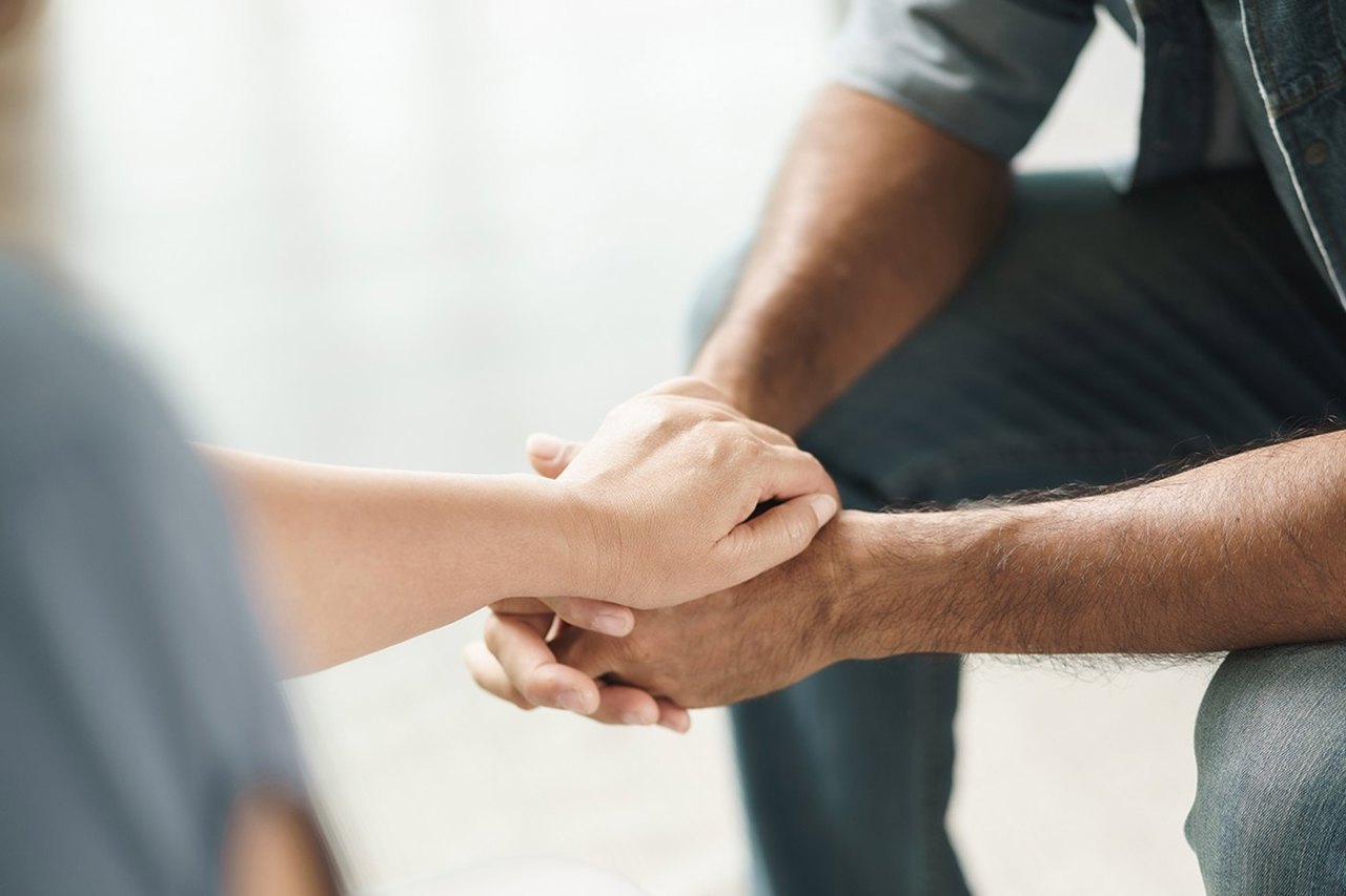 Two people holding hands in support
